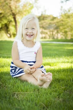 Cute Little Girl Sitting and Laughing in the Grass Outside.