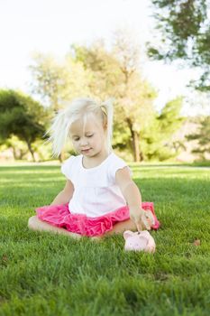 Cute Little Girl Having Fun with Her Piggy Bank Outside on the Grass.