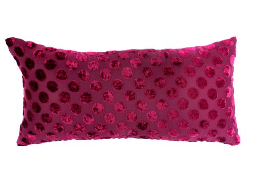 A luxurious pink pillow with a beautiful polka design on pink fabric, on white studio background