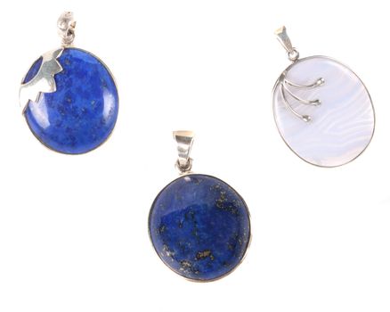 A set of three pendants made of precious gemstones, on white studio background.