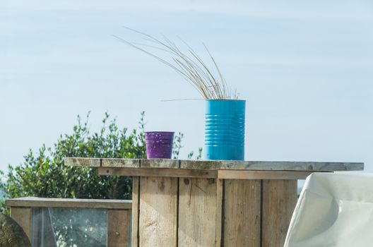 Still life on the beach, travel, tourism, two colorful tin cans on a weathered wooden table.
