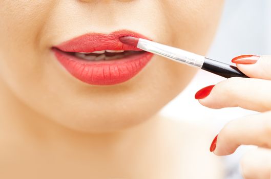 Woman applying red lipstick. Close-up view on face
