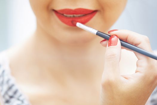 Woman applying red lipstick. Close-up view on face