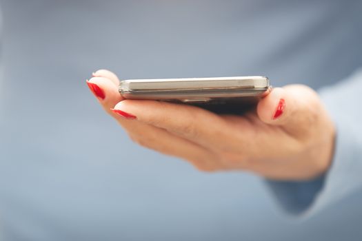 Woman with red manicure with smartphone. Horizontal photo