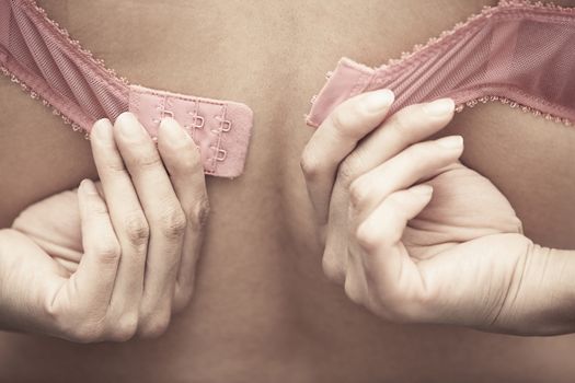 Hands of woman dressing pink brassiere