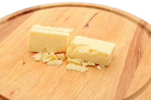 Small blocks of crumbly cheddar cheese on a wooden board