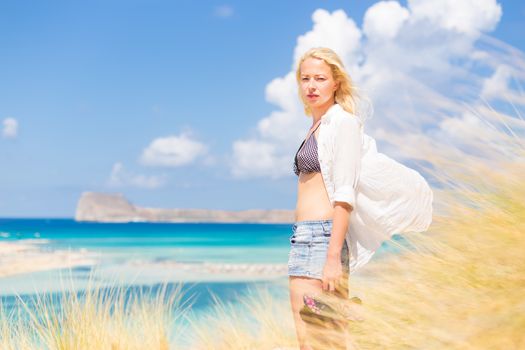 Relaxed woman enjoying freedom and life an a beautiful sandy beach.  Young lady feeling free, relaxed and happy. Concept of freedom, happiness, enjoyment and well being.  Enjoying Sun on Vacations.