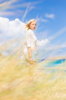 Relaxed woman enjoying freedom and life an a beautiful sandy beach.  Young lady feeling free, relaxed and happy. Concept of freedom, happiness, enjoyment and well being.  Enjoying Sun on Vacations.