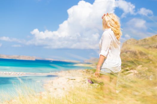 Relaxed woman enjoying freedom and life an a beautiful sandy beach.  Young lady feeling free, relaxed and happy. Concept of freedom, happiness, enjoyment and well being.  Enjoying Sun on Vacations.