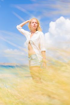 Relaxed woman enjoying freedom and life an a beautiful sandy beach.  Young lady feeling free, relaxed and happy. Concept of freedom, happiness, enjoyment and well being.  Enjoying Sun on Vacations.