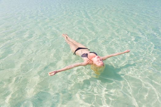 Beautiful Caucasian woman floating in turquoise blue lagoon.