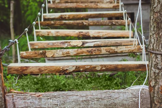 Wooden stairs in the green forest park with ropes