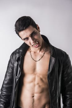 Portrait of a Young Vampire Man in an Open Black Leather Jacket, Showing his Chest and Abs, Looking at the Camera, on a White Background.