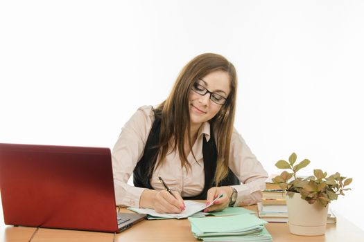 Cute little girl is a teacher sitting at a desk with a laptop, books and notebooks