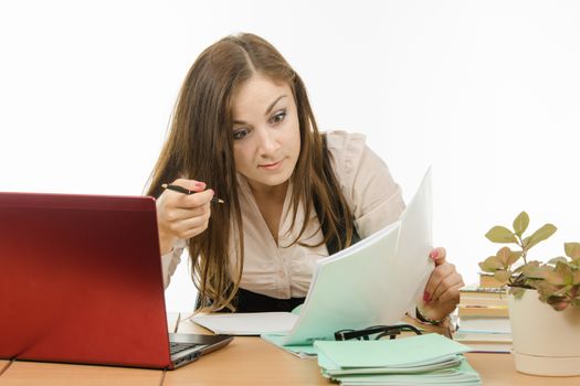 Cute little girl is a teacher sitting at a desk with a laptop, books and notebooks