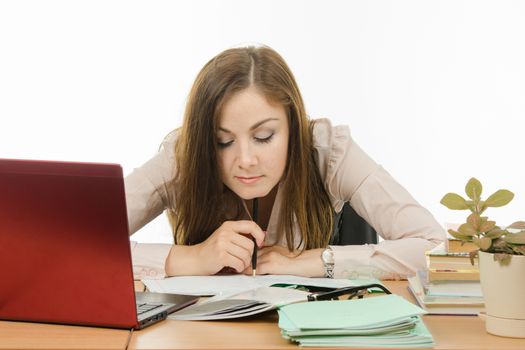 Cute little girl is a teacher sitting at a desk with a laptop, books and notebooks