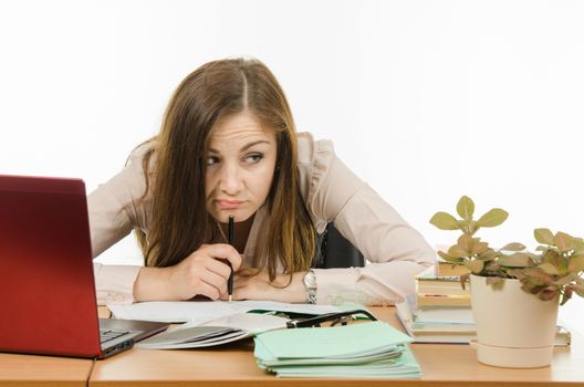 Cute little girl is a teacher sitting at a desk with a laptop, books and notebooks