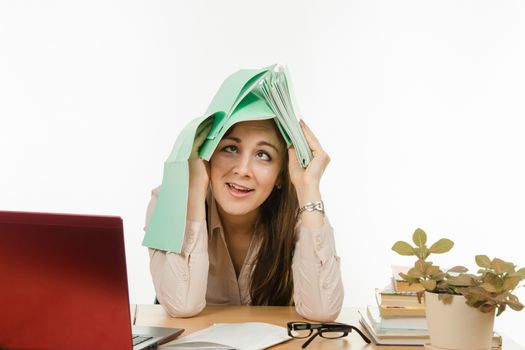 Cute little girl is a teacher sitting at a desk with a laptop, books and notebooks