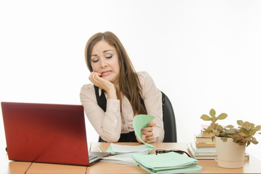 Cute little girl is a teacher sitting at a desk with a laptop, books and notebooks