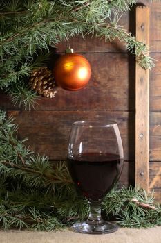 Christmas decoration. Red wine near spruce twigs against old wooden background