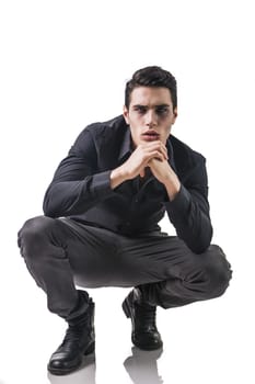 Portrait of a Young Vampire Man with Black Shirt Sitting on Floor with Hands Joined, Isolated on White