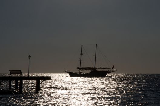 Seascape with Sailing Ship and Pier with Street Lamp Early Morning on Sunrise Sea background Outdoors