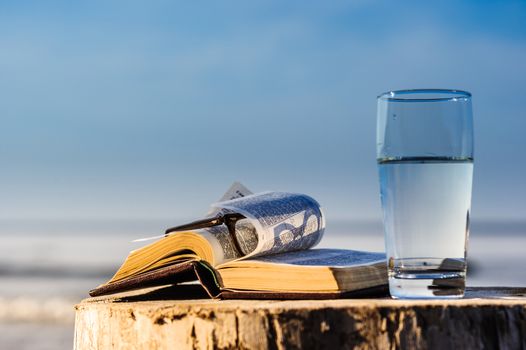 Open Bible and a glass of water on the coast