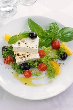 Cubes of feta cheese in oil with spices, cherry tomatoes and olives