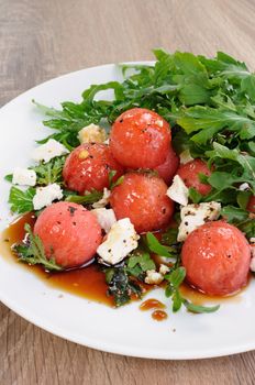 Spicy salad of watermelon balls with arugula and slices of feta