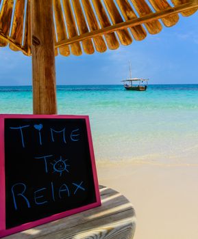 In the picture a Zanzibar beach which is a small blackboard with the words " Time to relax" in the afternoon .