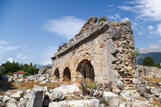 View of stones of destroyed and damaged Tlos Ancient City, on blue sky background.