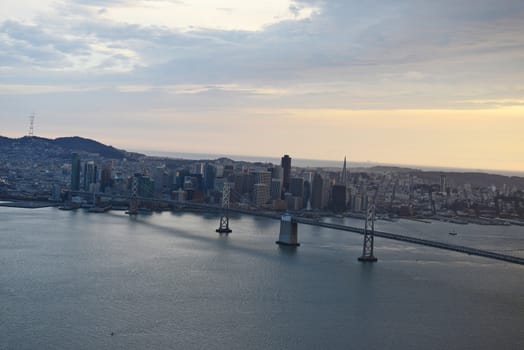 an aerial view of bay bridge near san francisco downtown during sunset, taken from a helicopter 