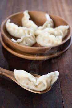 Fresh dumplings with hot steams on wood spoon. Famous Chinese cuisine on rustic old vintage wooden background. 