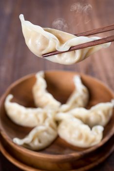 Fresh dumplings with wood chopstick. Popular Chinese food on rustic old vintage wooden background. 