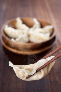 Fresh dumplings with wood chopstick. Famous Chinese food on rustic old vintage wooden background. 