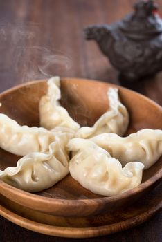 Fresh dumplings with hot steams on wood plate. Famous Chinese gourmet on rustic old vintage wooden background. 