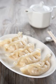 Fresh boiled dumpling on plate. Chinese food on old wooden background. 