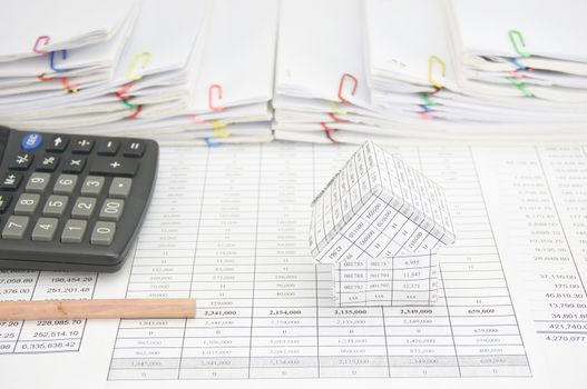 House and pencil with calculator on finance account have step overload of old paperwork as background.