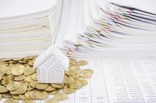 House with stack of gold coins on finance account have paper of report and step overload of old paperwork as background.