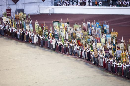 RIGA, LATVIA - JULY 4, 2013: Participants of Grand Dance Performance of the Latvian Nationwide Song and Dance Celebration with collective flags at Daugava stadium.