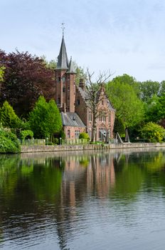 Flemish style castle reflecting in Minnewater lake, Fairytale scenery in Bruges, Belgium
