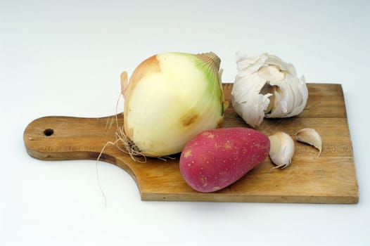   	potato, garlic, onion on a wooden cooking plate