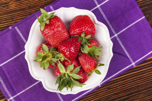 Ripe strawberries on rustic wooden brown table, top view. Healthy fruit eating.