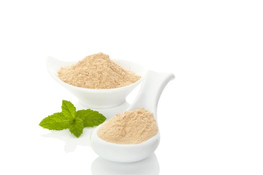 Maca powder on spoon and in a bowl and mint leaf isolated on white background. Natural alternative medicine.