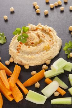 Fresh delicious hummus and fresh vegetables, chickpea and herbs. Traditional hummus eating.  