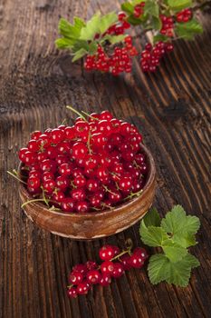 Red currant on wooden background. Healthy summer fruit eating.