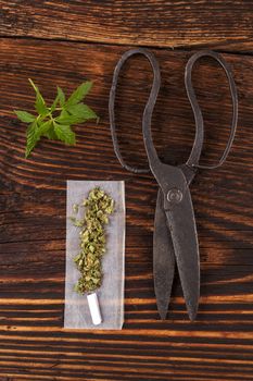 Marijuana abuse. Cannabis bud, joints, rolling paper on wooden textured background. 