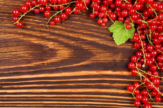 Red currant on wooden background. Healthy summer fruit eating.
