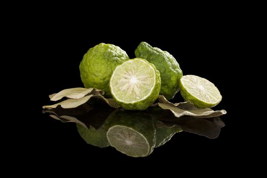 Dried bergamot leaves and fresh fruits isolated on black background. Culinary cooking, tropical fruit bergamot orange.