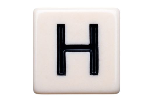 A macro shot of a game tile with the letter H on it on a white background.
